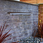 Garden fountain built into a grey garden wall.