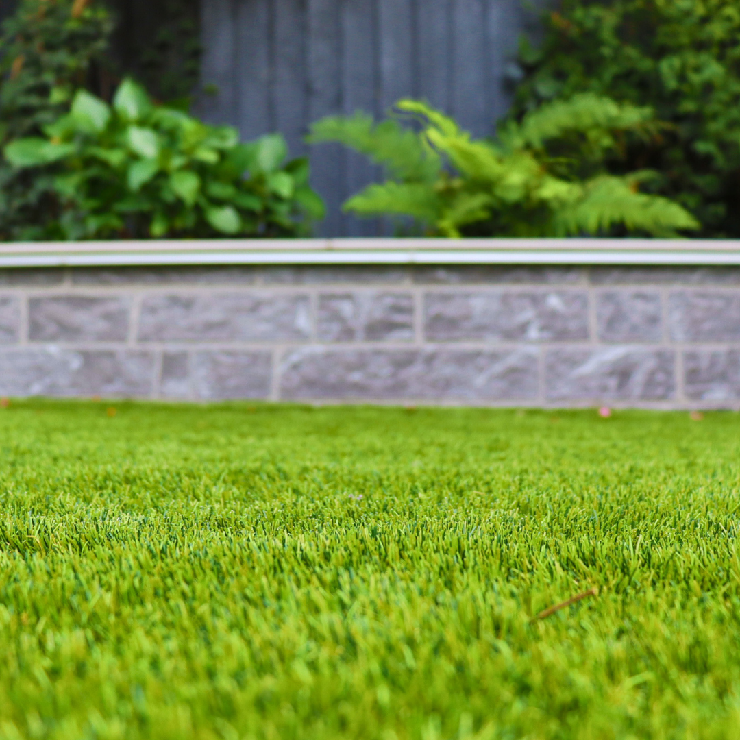Select Living Group Artificial Grass with a small grey garden wall in the background.