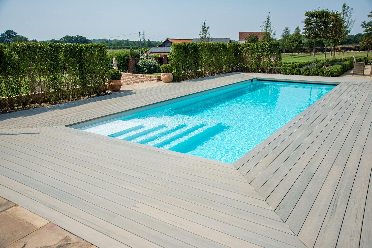 Swimming pool with composite decking from Select Living Group and greenery in the background