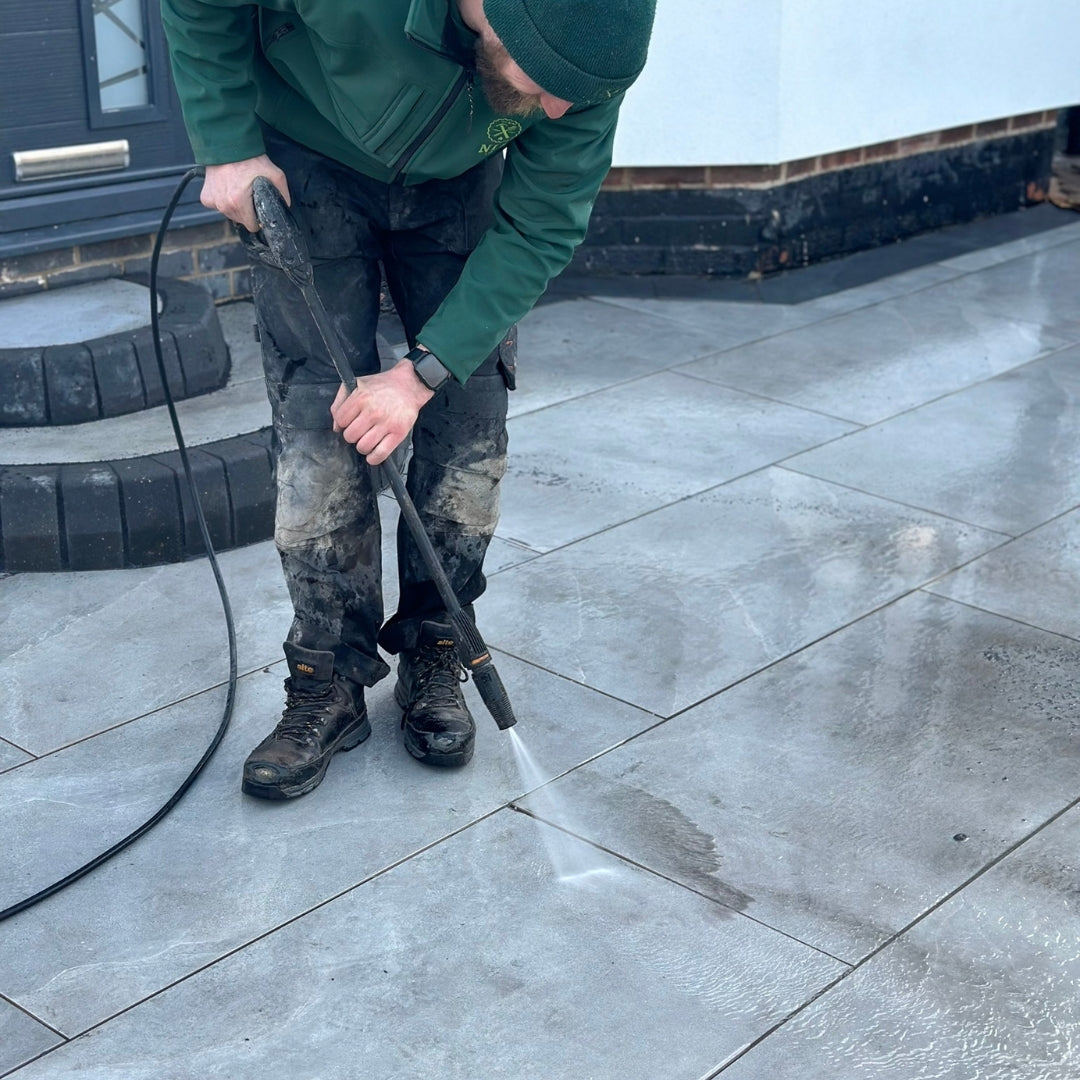 Person cleaning a Select Living concrete surface with a pressure washer .