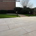 Paved patio area with grass and trees in the background, featuring Cristallo Beige Porcelain Paving from Select Living Group.
