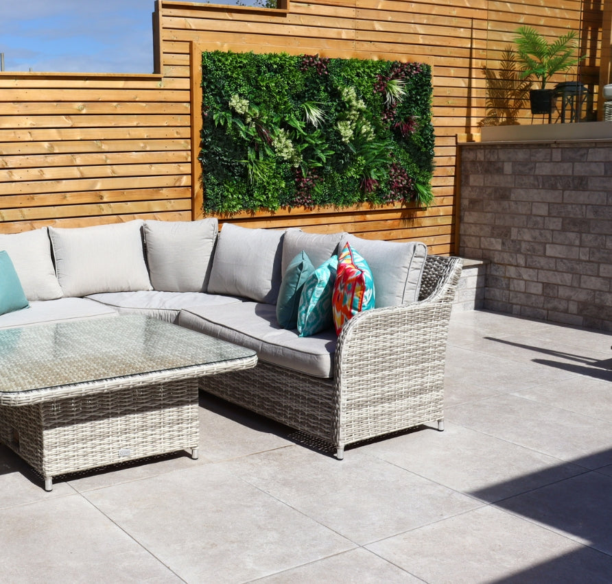 Outdoor patio with wicker sectional sofa, glass coffee table, and a select Living Group living wall on wooden fence.