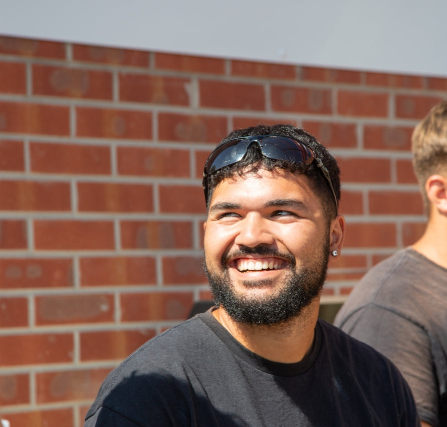 Tradesman with sunglasses on his head smiling in front of a brick wall outside Select Living Group